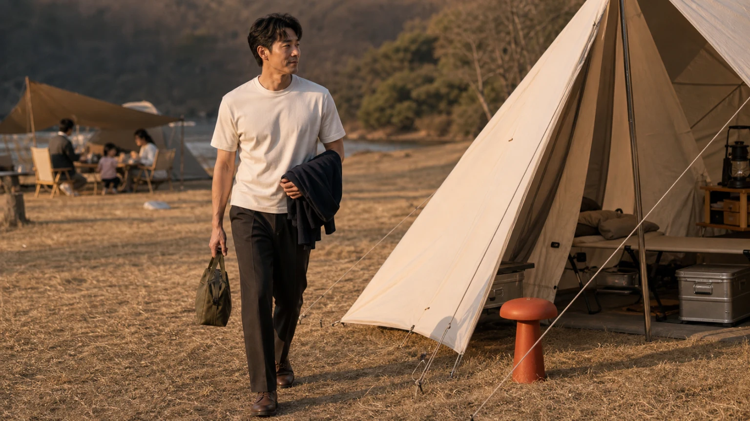 해 질 무렵 가벼운 겉옷을 조정하며 캠핑 공간으로 이동하는 남성