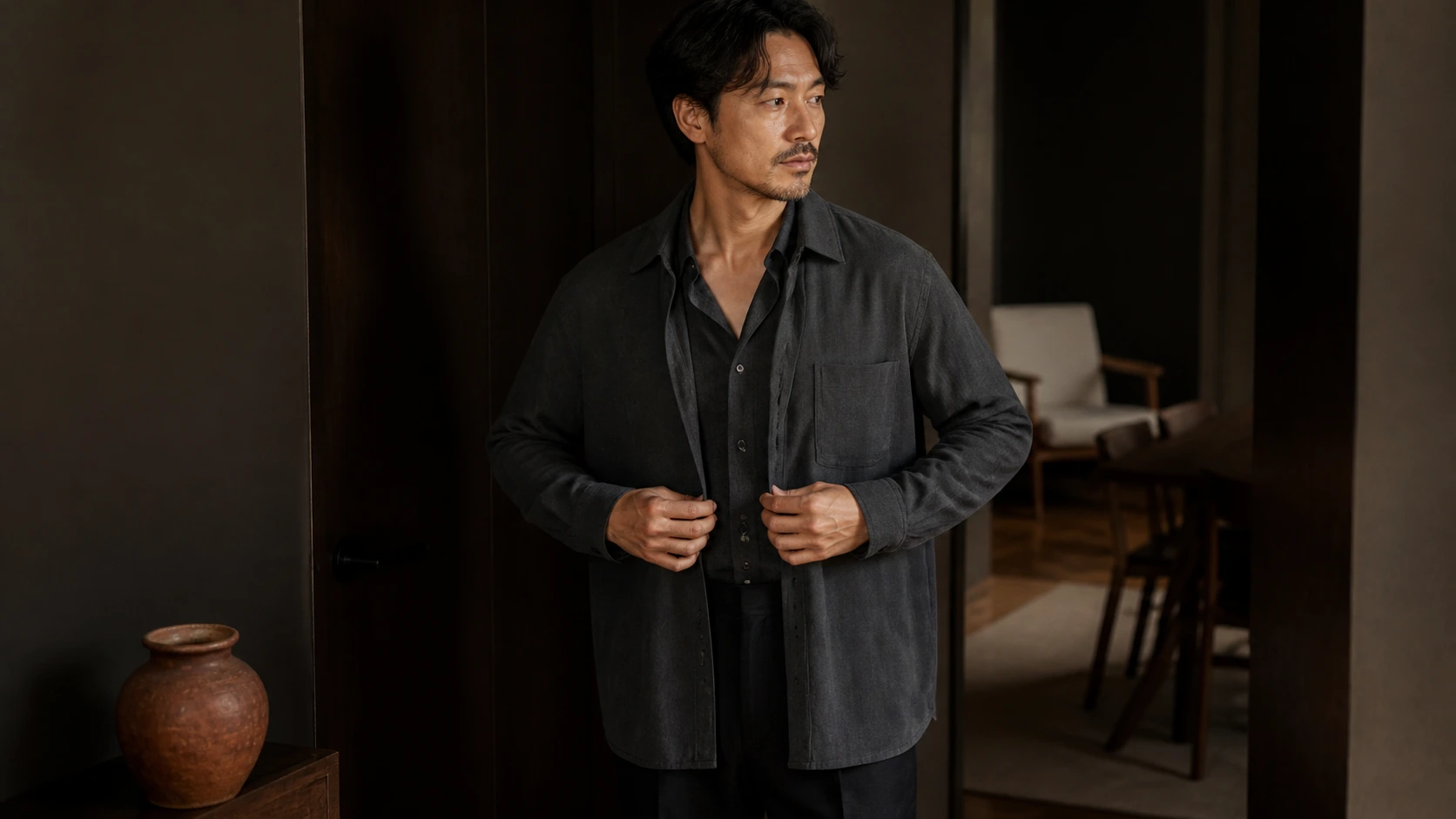 현관 가까운 실내에서 겉옷과 레이어를 정리하는 남성