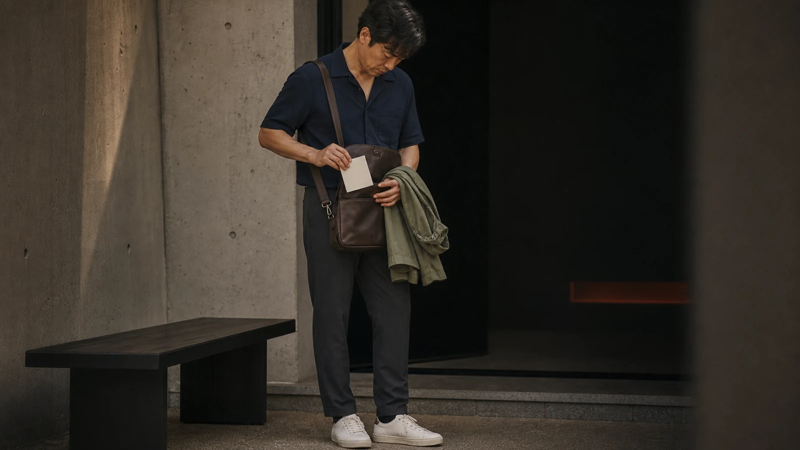입장 전 작은 가방과 가벼운 레이어를 확인하는 남성